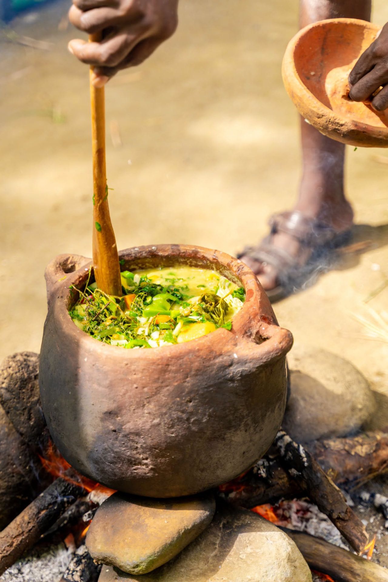 Creole cook stirring a pot over an open wood fire